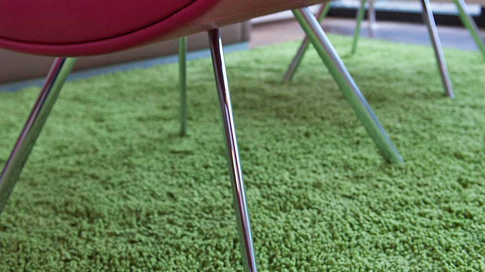 Grüner Teppichboden mit rotem Lounge-Sessel